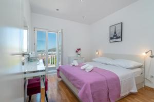 a white bedroom with a large bed with a purple blanket at Apartments Kapetan in Trogir +98 photos