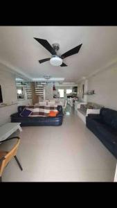 ein Wohnzimmer mit einem Deckenventilator und einem Sofa in der Unterkunft Casa de Praia em Condomínio Fechado in Guarujá + 23 Fotos
