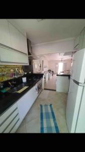 eine Küche mit weißen Geräten und einem blauen Streifen auf dem Boden in der Unterkunft Casa de Praia em Condomínio Fechado in Guarujá