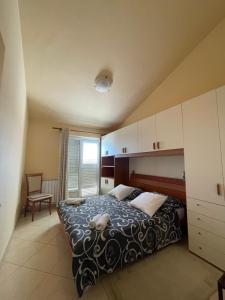 Un dormitorio con una cama y una silla y una ventana. en Apartment Nikola, en Rogoznica