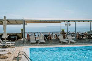 un complejo con piscina, mesas y sillas en Arilla Beach Hotel, en Perdika