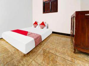 1 dormitorio con cama blanca y armario de madera en OYO Homes 91134 Desa Wisata Tebing Lingga 