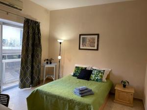 a bedroom with a green bed with a window at Olivier House Mellieha in Mellieħa