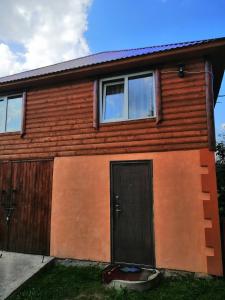 Casa de madera con puerta y ventanas negras en У Катерини, en Dvozhets