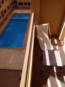 a balcony with a chair and a swimming pool at Agréable appartement au coeur de Guéliz, Marrakech in Marrakech