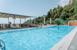 a pool at a hotel with people in the water at Arilla Beach Hotel in Perdika