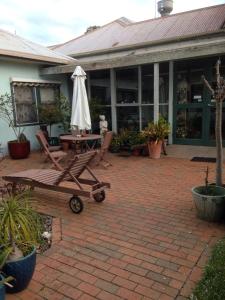 a patio with a table with an umbrella on it at Butlers Guesthouse in Birregurra