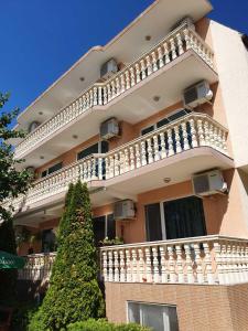 un gran edificio de apartamentos con balcón y un árbol en Villa Amadeus, en Nesebar