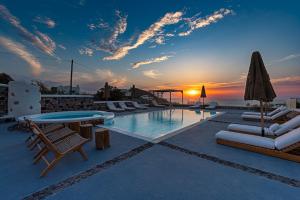 une piscine avec des chaises et un coucher de soleil en arrière-plan dans l'établissement Symmetry Suites, à Akrotiri