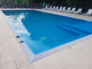 a large blue swimming pool with chairs and chairs at Anthimos in Baile Felix