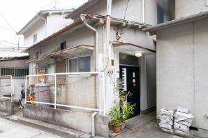 un edificio con una valla y una puerta con una planta en Unique joy House, en Okayama