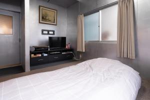 岡山市にあるUnique joy Houseのベッドルーム(白いベッド1台、テレビ付)