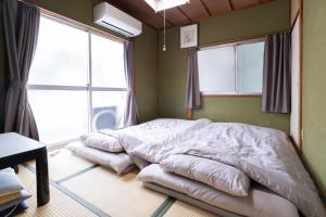 a bed in a room with two large windows at Unique joy House in Okayama