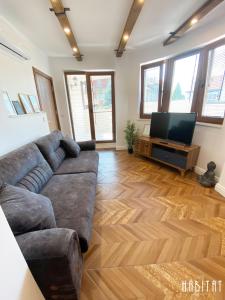 ein Wohnzimmer mit einem Sofa und einem Flachbild-TV in der Unterkunft Habitat Central Apartment in Ruse
