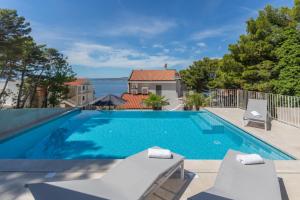 a swimming pool with two chairs and a house at Brela - room for two in Brela