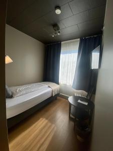 um quarto com uma cama, uma mesa e uma janela em North West Restaurant & Guesthouse em Víðigerði