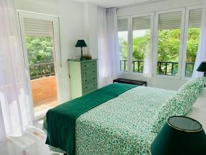 a bedroom with a bed with a green bedspread and windows at FAISÁN 20 Apartamento in Granada