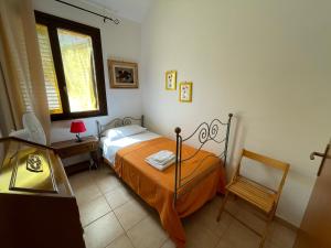 a bedroom with a bed and a chair and a window at Villa Barraco Paradise in San Vito lo Capo