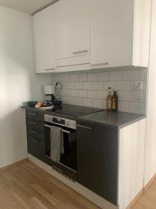 cocina con fogones negros y armarios blancos en Modern one bedroom apartment nearby Airport en Vantaa