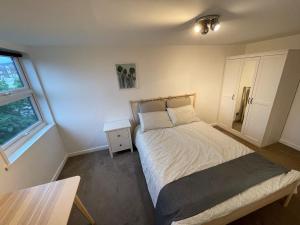 ein kleines Schlafzimmer mit einem Bett und einem Fenster in der Unterkunft Spacious 2-Bedroom Flat Near Surbiton Station in Surbiton