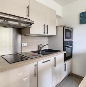 a kitchen with white cabinets and a sink and a microwave at Studio - 1 minute de la plage et de la Promenade des Anglais in Nice