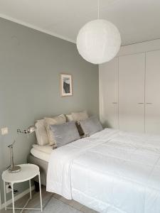a white bedroom with a large bed and a lamp at Modern one bedroom Apartment with Sauna near Airport in Vantaa