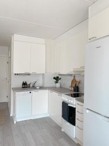 a white kitchen with white cabinets and white appliances at Modern one bedroom Apartment with Sauna near Airport in Vantaa