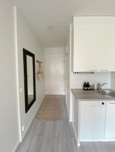 a kitchen with white cabinets and a sink and a mirror at Modern one bedroom Apartment with Sauna near Airport in Vantaa