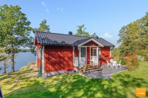 a red tiny house with a patio and a lake at Ekudden. Idylliskt nära sjö. Egen strand. in Rimforsa