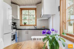 a kitchen with a wooden table with purple flowers at Ekudden. Idylliskt nära sjö. Egen strand. in Rimforsa