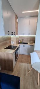 a kitchen with white cabinets and a sink and a chair at APARTAMENT SORENTO 37 in Gorzów Wielkopolski