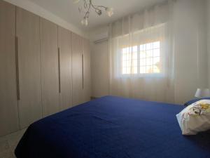 a bedroom with a blue bed and a window at Marsala beddra lu suli, lu Mari e lu ventu in Marsala