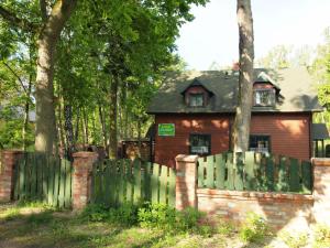 ein Haus hinter einem Gartenzaun mit grünem in der Unterkunft Domki Klara in Pobierowo