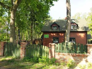 a house behind a picket fence with a green at Domki Klara in Pobierowo