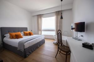 a bedroom with a bed with orange pillows and a desk at Unìco Boutique Hotel d'Arte in Mondello