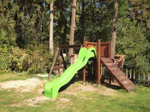 un parque infantil con un tobogán verde en el césped en Domki Klara, en Pobierowo
