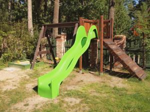 a playground with a green slide in the grass at Domki Klara in Pobierowo +15 photos