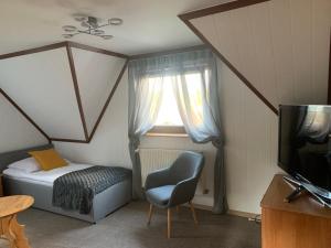 a bedroom with a bed and a chair and a television at Willa Rokita in Zakopane
