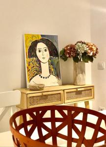 a painting of a woman on a table with a chair at Precioso piso en el centro neurálgico de Olot in Olot