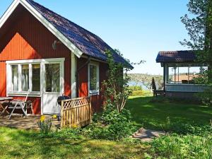 una pequeña casa roja con porche y cenador en Holiday home in Vreta en Borensberg