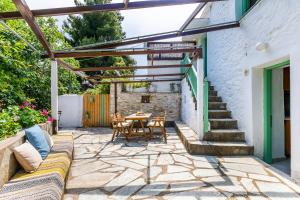 a patio with a table and chairs under a pergola at La Belle Merle in Panormos Skopelos