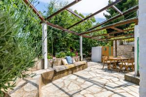 a patio with a couch under a pergola at La Belle Merle in Panormos Skopelos