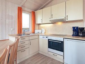een keuken met witte apparatuur en een oranje gordijn bij 4 person holiday home in GROEMITZ in Grömitz