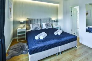 - une chambre dotée d'un grand lit avec des draps et des oreillers bleus dans l'établissement Klif Resort Apartamenty, à Mechelinki