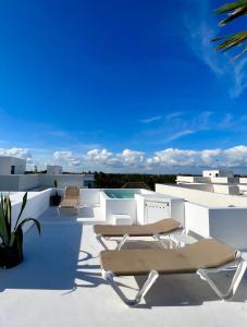a patio with chairs and a swimming pool on a roof at Amazing Luxury Penthouse with sunset,sunrise view, private Jacuzzi and rooftop pool in Tulum
