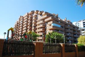 ein hohes Gebäude mit einem Zaun davor in der Unterkunft Apartamentos Be Suites Mar de Azahar in Oropesa del Mar