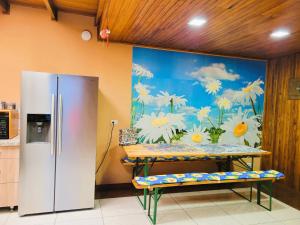 a kitchen with a refrigerator and a wall with a mural at Casa Flores in Heredia