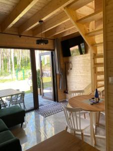 a living room of a wooden house with a table and chairs at Jarzębinowy Zakątek in Kopalino