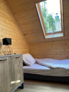 a bed in a wooden room with a window at Jarzębinowy Zakątek in Kopalino