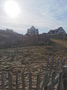 una valla en la playa con una casa en el fondo en Cabourg T2 Front de Mer - Proche Thalasso, en Cabourg